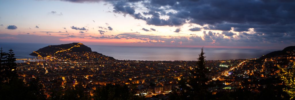 Panoramic night view of peninsula in Antalya, Alanya Castle with lighting in blue hours.