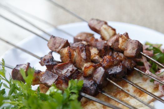 Close up detailed view of grilled delicious liver shish kebab of Turkey served on a white plate with parsley and onion.