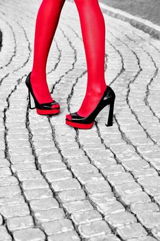Fashion urban womens legs, red pantyhose, stylish shiny heels. Geometry square pattern, outdoor. Trendy shoes, Black and white, paving stone 