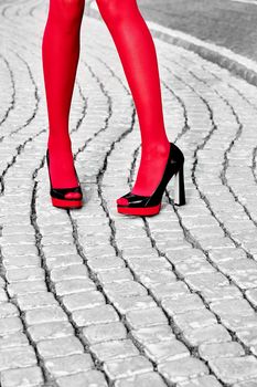 Fashion urban womens legs, red pantyhose, stylish shiny heels. Geometry square pattern, outdoor. Trendy shoes, Black and white, paving stone 