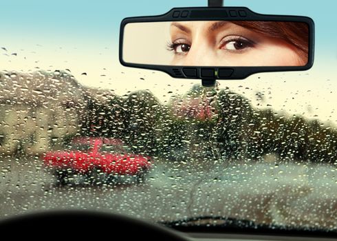 woman sits on driver's seat and Looks in the rear-view mirror