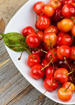 Fresh Ripe Sweet Maraschino Cherries with Leaf in White Bowl closeup on Rustic Wooden background