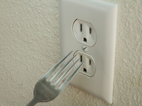 Kid trying to put a metal fork into an electrical outlet