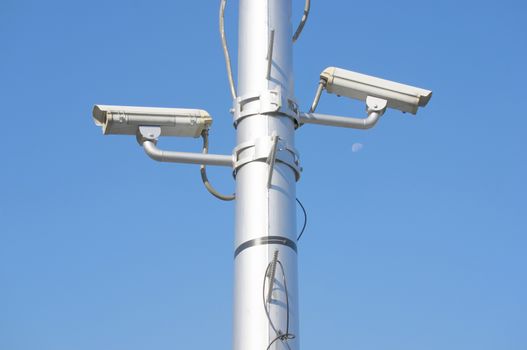 Security camera on high pole at super highway with blue sky.