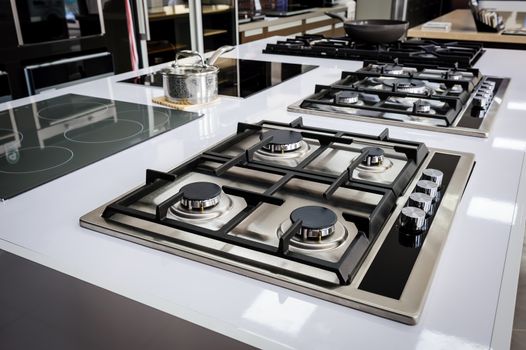 Rows of gas stoves with stainless tray selling in appliance retail store