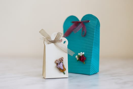 Close up detailed front view of hand-crafted green and white gift boxes with small flowers and colorful ribbons.