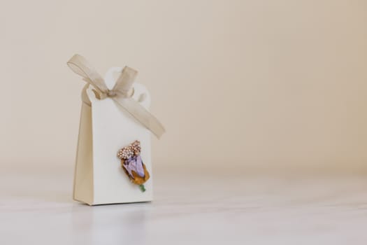 Close up detailed front view of hand-crafted white gift box with small flowers and colorful ribbons.