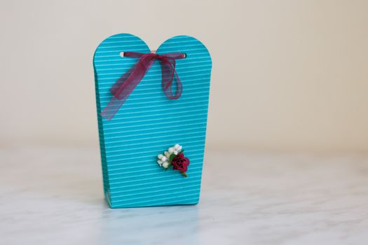 Close up detailed front view of hand-crafted green gift box with small flowers and colorful ribbons.