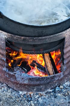 Preparing food on big pot, outside on wooden fire