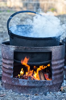 Preparing food on big pot, outside on wooden fire