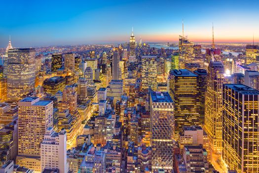 New York City. Manhattan downtown skyline with illuminated Empire State Building and skyscrapers at dusk.