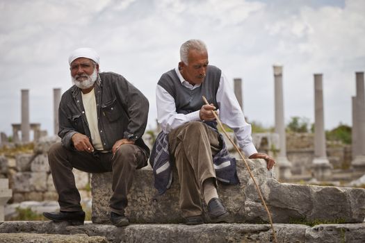 PERGA, ANATOLIA, TURKEY – APRIL 18: Two Turkish men in the ruins of Perga on April 18, 2012 in Perga, Anatolia, Turkey. 