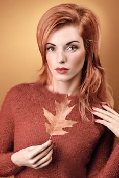 Beauty portrait redhead young woman with autumn leafs in hands. Attractive happy girl dreams, romantic. People face closeup, makeup. Retro, vintage, creative toned, orange yellow background, copyspace