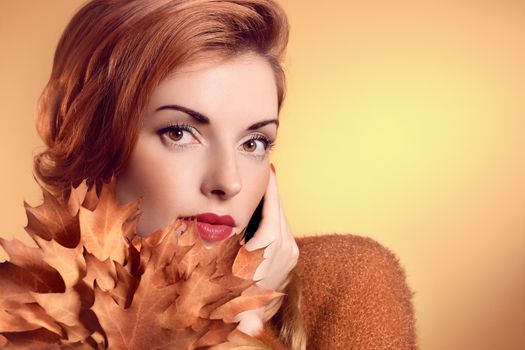 Beauty portrait redhead young woman with autumn leafs in hands. Attractive happy girl dreams, romantic. People face closeup, makeup. Retro, vintage, creative toned, orange yellow background, copyspace