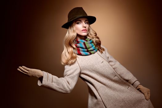 Fashion beauty woman in stylish long coat, hat. Autumn winter model blonde girl with long blonde wavy hair in colored striped scarf, gloves. Unusual creative attractive people. Retro Vintage,copyspace