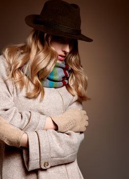 Fashion beauty woman in stylish long coat, hat. Autumn winter model blonde girl with long blonde wavy hair in colored striped scarf, gloves. Unusual creative attractive people. Retro Vintage,copyspace