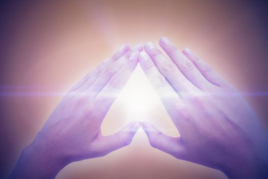 Woman making heart shape with hands against orange background