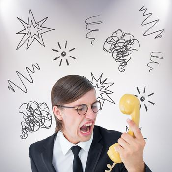 Geeky businessman shouting at retro phone  against grey background