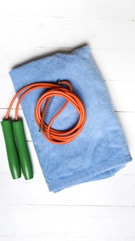 fitness equipment:blue towel,jumping rope on white wood table