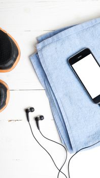 fitness equipment:running shoes,blue towel and smart phone on white wood table