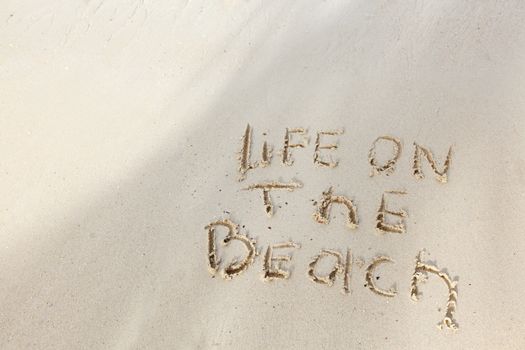 Life on the beach concept - inscription on a beach sand with coming wave