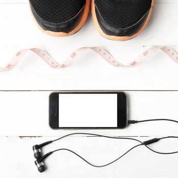 running shoes,measuring tape and phone on white wood table