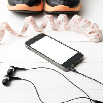 running shoes,measuring tape and phone on white wood table