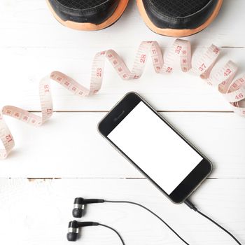 running shoes,measuring tape and phone on white wood table