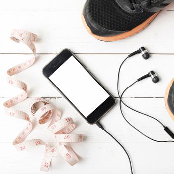 running shoes,measuring tape and phone on white wood table