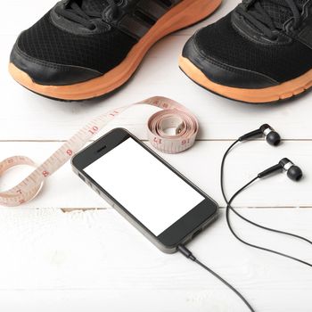 running shoes,measuring tape and phone on white wood table