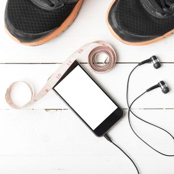 running shoes,measuring tape and phone on white wood table