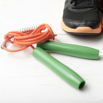 running shoes and jumping rope on white table