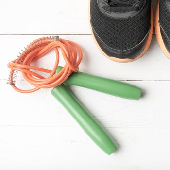 running shoes and jumping rope on white table