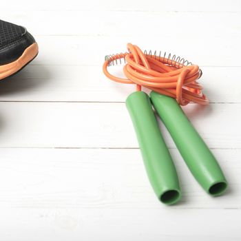 running shoes and jumping rope on white table