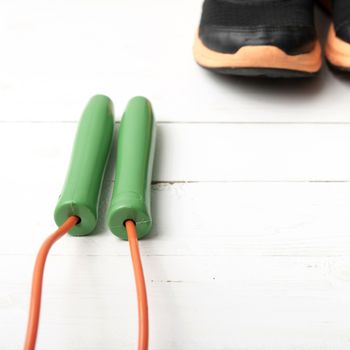 running shoes and jumping rope on white table