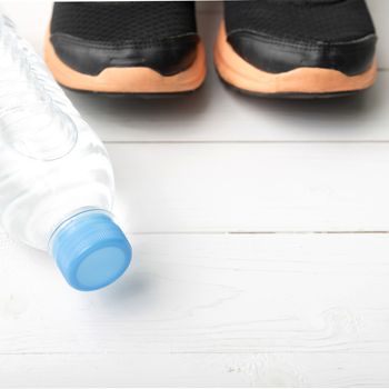 running shoes and drinking water on white table