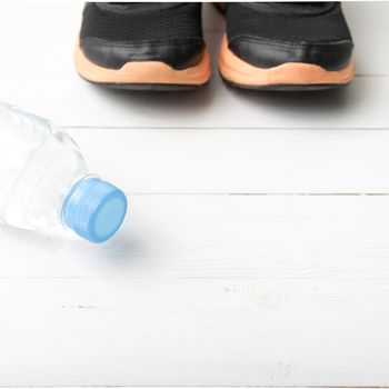 running shoes and drinking water on white table