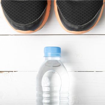 running shoes and drinking water on white table