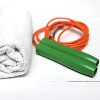 fitness equipment:white towel,jumping rope on white wood table