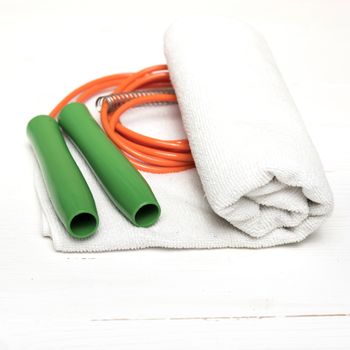 fitness equipment:white towel,jumping rope on white wood table