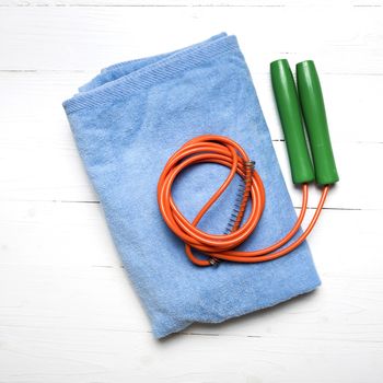 fitness equipment:blue towel,jumping rope on white wood table