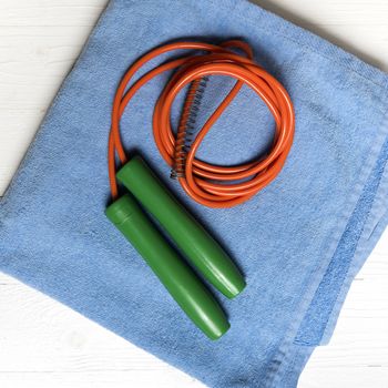 fitness equipment:blue towel,jumping rope on white wood table