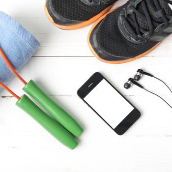 fitness equipment : running shoes,towel,jumping rope and phone on white wood table