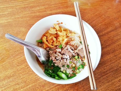 Thai noodles in bowl on wood table with chopsticks and spoon