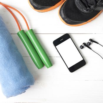 fitness equipment : running shoes,towel,jumping rope and phone on white wood table