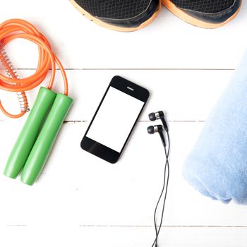 fitness equipment : running shoes,towel,jumping rope and phone on white wood table