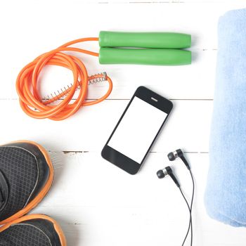 fitness equipment : running shoes,towel,jumping rope and phone on white wood table