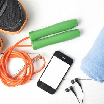 fitness equipment : running shoes,towel,jumping rope and phone on white wood table