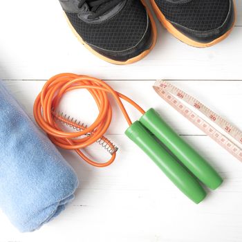 fitness equipment : running shoes,towel,jumping rope and measuring tape on white wood table