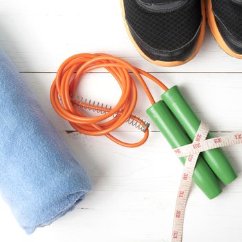fitness equipment : running shoes,towel,jumping rope and measuring tape on white wood table